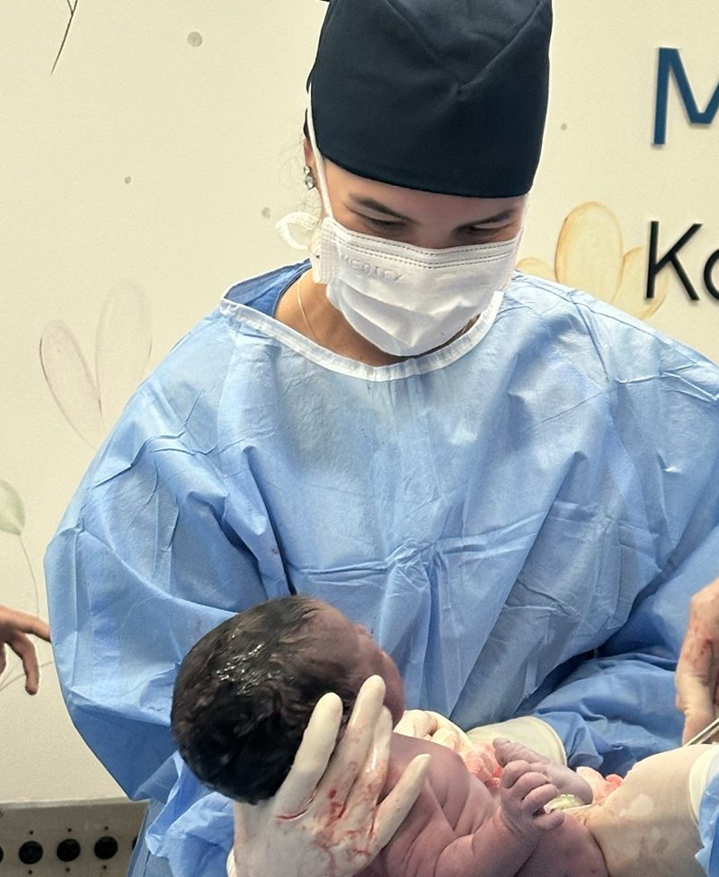 Dra. Amanda Galdino segurando um recém-nascido no parto